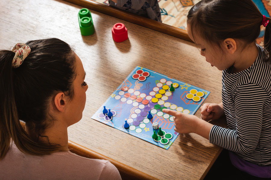 Mother and daughter playing board game at home.
